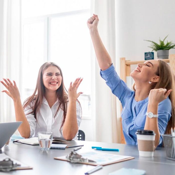 Mujeres celebrando en oficina moderna, el poder realizar el servicio de desconexión digital con éxito.